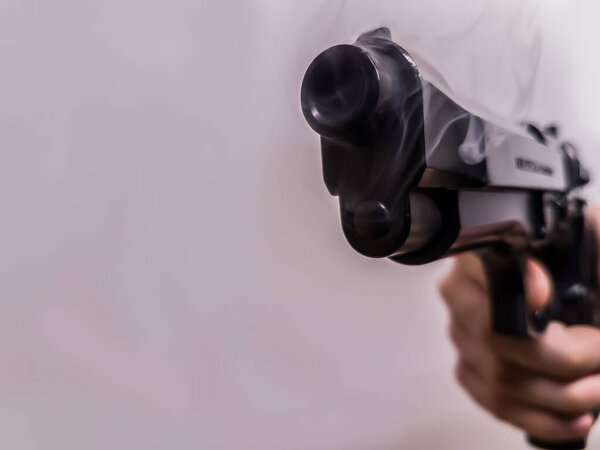 Пистолет с дымящимся стволом после выстрела
