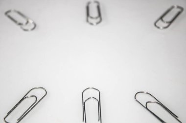 Metalik zımbalar, gümüş renginde, beyaz bir yüzeye yerleştirilmiş, görüntünün kenarları boyunca bir çerçeve oluşturuyor.