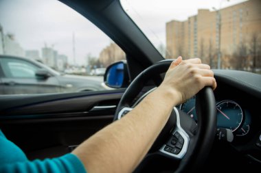 Tanınmayan bir kadın sağ elini direksiyonda tutuyor ve siyah bir iç mekanı olan modern bir araba kullanıyor. Dışarıda bir gün. Kız arabasına biniyor. yakın plan, yumuşak odak, bulanık arkaplan