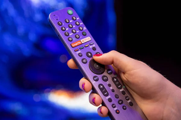 Moskova, Rusya - Ekim 04, 2019: Kadın eli Netflix tuşlu ve mikrofon ve ses kontrollü akıllı TV uzaktan kumandası tutuyor. arkaplan bulanık.
