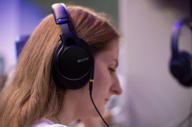 M. Moskova, Rusya - Ekim 04, 2019: Genç sarışın kadın kulaklıkla müzik dinliyor Sony mdr-1am2, yan görüş, yumuşak odaklanma