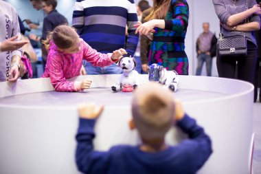 Moskova, Rusya - Ekim 04, 2019: Çocuk kız, Sony Pet robot teknolojisi tarafından tasarlanan ve üretilen Aibo Robotik evcil hayvanlarla oynar. Ön taraf bulanık, yumuşak odaklı..