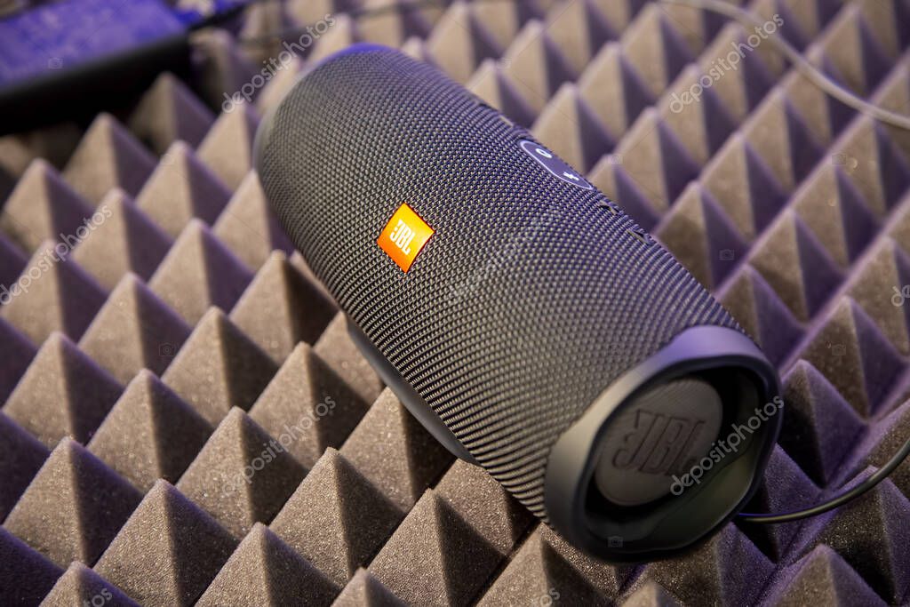 Moscow, Russia - October 04, 2019: close up of black portable bluetooth waterproof music speaker JBL Charge 4 rests on noise reduction cover. soft focus, background in blur