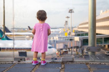 Çocuk havaalanındaki uçaklara bakıyor ve uçağa binmeyi bekliyor. arka plan