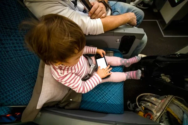 entertainment on board the aircraft in flight. baby sit on the plane in the seat and holds a multimedia system with a white screen copyspace