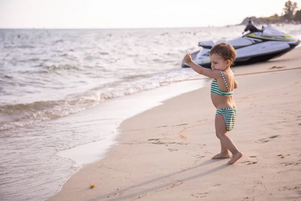 Mały słodkie dziecko biegnie wzdłuż plaży morskiej w słoneczny ciepły dzień. — Zdjęcie stockowe