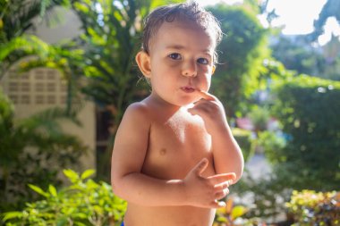 Güneşli bir günde ağzını kurabiyelerle dolduran kameraya bakan tatlı çocuk.