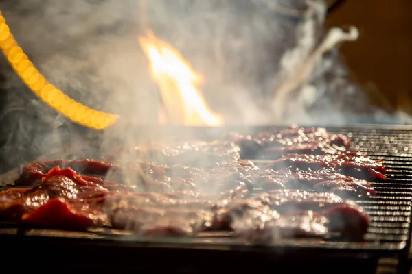 Večer se na grilu grilují lahodné šťavnaté steaky na otevřeném ohni. zblízka, měkké soustředění. kouř je zvýrazněn — Stock fotografie
