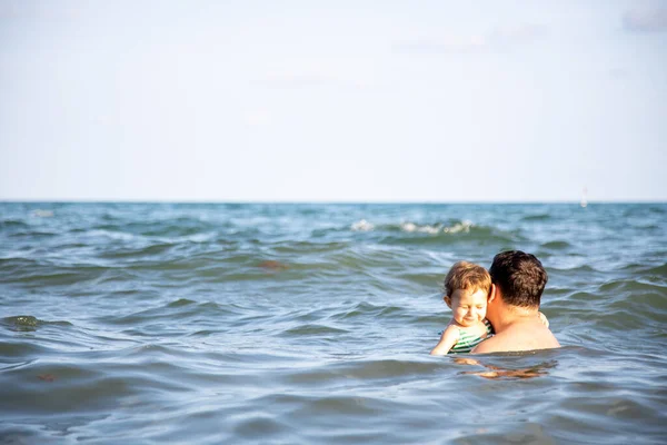 Fatherly love concept. best dad. father hugs little cute toddler daughter in the water of the sea — Stock Photo, Image