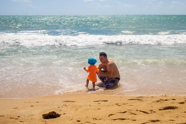 父の日。父は赤ちゃんに海岸を歩くように教えています — ストック写真
