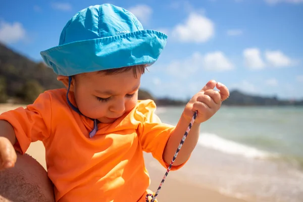 Dziecko siedzi w ramionach taty na plaży morskiej i bawi się liną — Zdjęcie stockowe