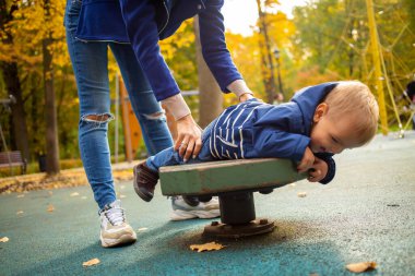 Mavi elbiseli anne ve bebek sonbahar parkında oyun oynuyorlar. Mutlu çocukluk kavramı