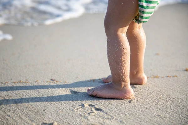 Zbliżenie dziecięce nóżki w piasku i falach morza — Zdjęcie stockowe