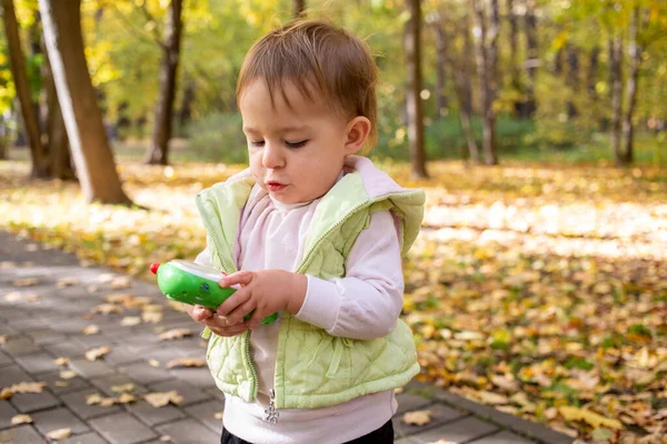 Милый малыш играет и держит игрушечный телефон в парке — стоковое фото