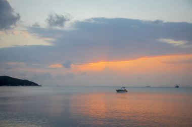 Sisli Günbatımı ve Suyun Yansıması ile Bir Yelkenli Teknesi