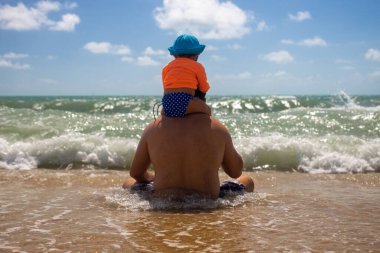 Baba ve bebek dalgaların kumsalda oturuşuna bakın.