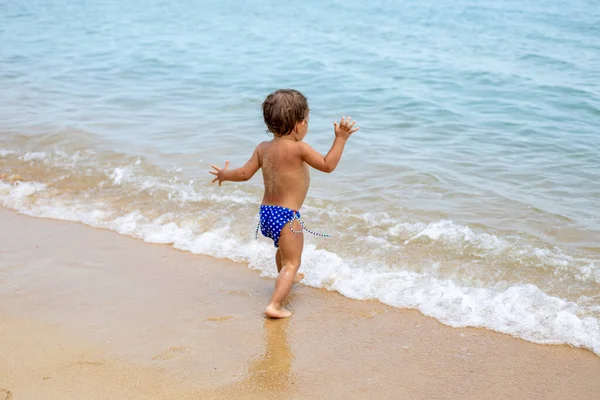 Adorable maluch biegać bawiąc się na piaszczystej plaży tropikalnego morza — Zdjęcie stockowe