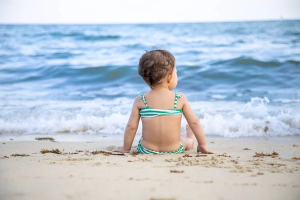 砂のビーチで波を壊す海に座っている女の子 — ストック写真