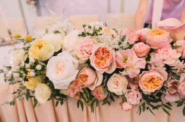 Ziyafet, restoran. Masa ayarı. Masanın üzerinde pembe bir masa örtüsü var. Presidium, yeni evlilerin masası. Masanın üzerinde bir masa örtüsü var. Şeftali pembesi renklerinde çiçek aranjmanları. Uzun mumlar.