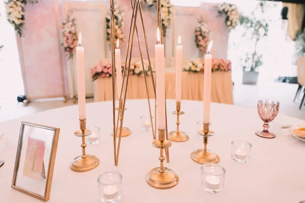 餐桌布置 白色盘子 金色餐具 有金戒指的桃色餐巾 桃红色的花的排列 金烛台上的高锥形蜡烛 — 图库照片