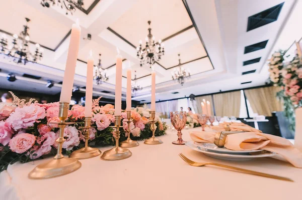 餐桌布置 桃红色的花的排列 金烛台上的高锥形蜡烛 — 图库照片