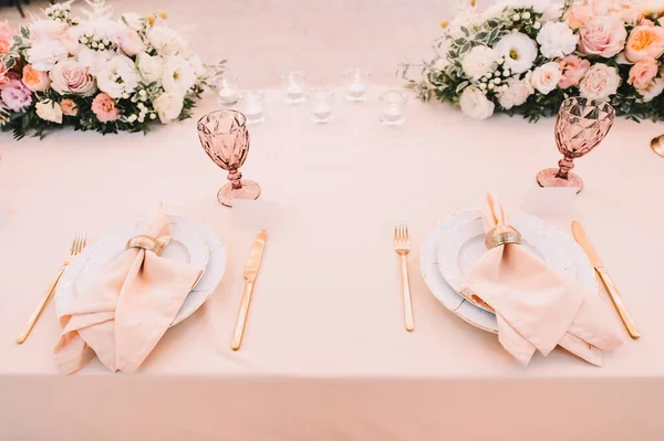 餐桌布置 白色盘子 金色餐具 有金戒指的桃色餐巾 桃红色花的排列 — 图库照片
