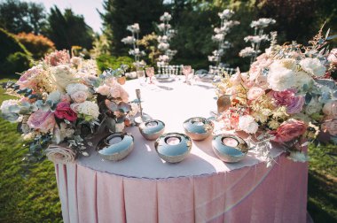 Presidium, yeni evlilerin masası. Çiçeklerin çiçek aranjmanları. Gümüş şamdanlar ve mumlar. Masanın üzerinde pembe kadife bir masa örtüsü var. Yeşil çimlerin üzerinde