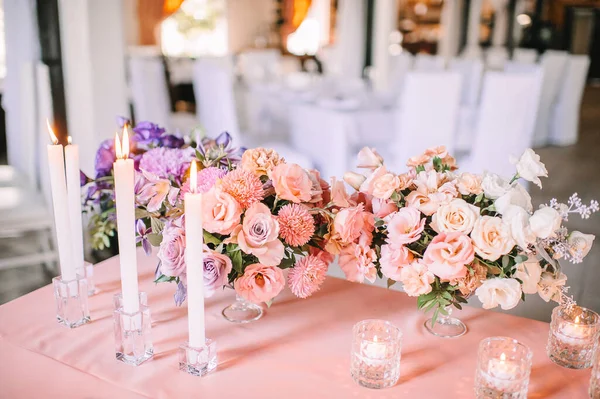 有粉色桌布的宴席 盘子和餐具 紫色眼镜 玻璃烛台上的蜡烛 康乃馨 — 图库照片