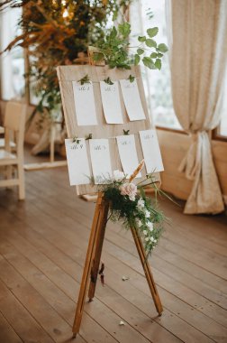 Oturma planı, sehpadaki ahşap tahta masa numaraları, çiçek ve tropik yapraklardan oluşan kağıt kağıtlar, ahududu dalları..