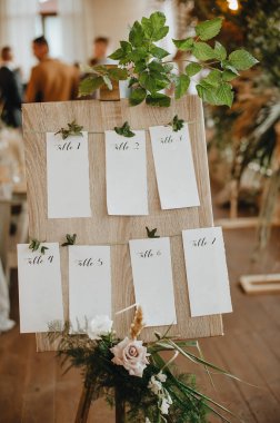 Oturma planı, sehpadaki ahşap tahta masa numaraları, çiçek ve tropik yapraklardan oluşan kağıt kağıtlar, ahududu dalları..