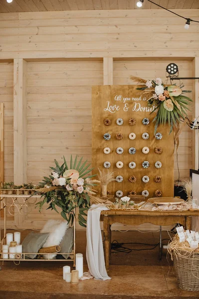 stock image Wooden board with various glazed donuts and powder. Caption: all we need is love and donuts. Arrangement of flowers and tropical leaves