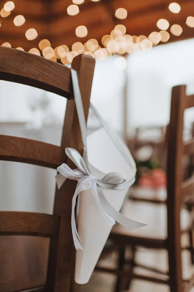 An envelope hangs on the back of a chair, a paper bag decorated with a ribbon