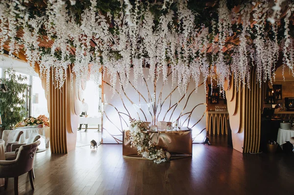 Modern ahşap arka plan, çelenk, iç mekan. Masalar servis edildi, çiçekler ve yeşillik kompozisyonları. Tabaklar, çatal bıçak takımı, peçete, pembe bardaklar. Yemek salonu..