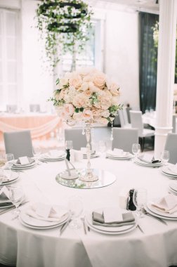 Restoran, ziyafet, sofra kurma. Masa beyaz bir masa örtüsü, bulaşıklar, beyaz temiz tabaklar, çatal bıçak takımı, peçeteler, şarap bardakları, mumlarla kaplı. Yakın plan..