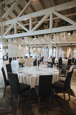 Restoran, iç mekan, ziyafet, masa düzenleme. Masa beyaz bir masa örtüsü, bulaşıklar, beyaz temiz tabaklar, çatal bıçak takımı, peçeteler, şarap bardakları, mumlarla kaplı. Genel plan.