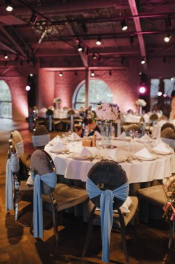 Restoran, iç mekan, ziyafet, masa düzenleme. Masa beyaz bir masa örtüsü, bulaşıklar, beyaz temiz tabaklar, çatal bıçak takımı, peçeteler, şarap bardakları, mumlarla kaplı. Genel plan.