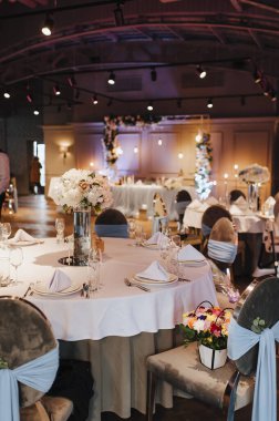 Restoran, iç mekan, ziyafet, masa düzenleme. Masa beyaz bir masa örtüsü, bulaşıklar, beyaz temiz tabaklar, çatal bıçak takımı, peçeteler, şarap bardakları, mumlarla kaplı. Genel plan.