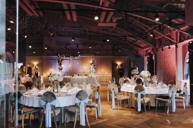 Restoran, iç mekan, ziyafet, masa düzenleme. Masa beyaz bir masa örtüsü, bulaşıklar, beyaz temiz tabaklar, çatal bıçak takımı, peçeteler, şarap bardakları, mumlarla kaplı. Genel plan.