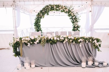 Restoran, iç mekan, ziyafet, masa düzenleme. Masa beyaz bir masa örtüsü, bulaşıklar, beyaz temiz tabaklar, çatal bıçak takımı, peçeteler, şarap bardakları, mumlarla kaplı. Genel plan.