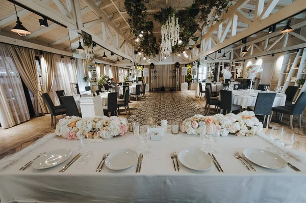 Restaurant, banquet, table setting. The table is covered with a white tablecloth, dishes, white clean plates, cutlery, napkins, wine glasses, candles. Close-up.