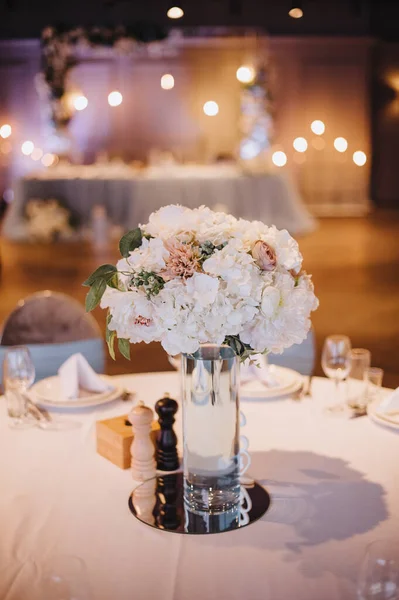 Restaurant, banquet, table setting. The table is covered with a white tablecloth, dishes, white clean plates, cutlery, napkins, wine glasses, candles. Close-up.