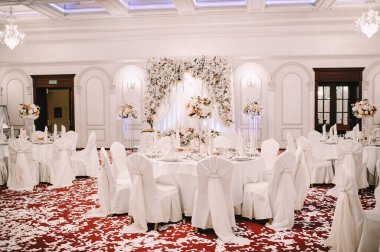 Restoran, ziyafet, sofra kurma. Masa beyaz bir masa örtüsü, bulaşıklar, beyaz temiz tabaklar, çatal bıçak takımı, peçeteler, şarap bardakları, mumlarla kaplı. Yakın plan..