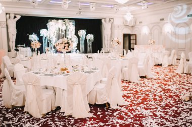 Restoran, ziyafet, sofra kurma. Masa beyaz bir masa örtüsü, bulaşıklar, beyaz temiz tabaklar, çatal bıçak takımı, peçeteler, şarap bardakları, mumlarla kaplı. Yakın plan..