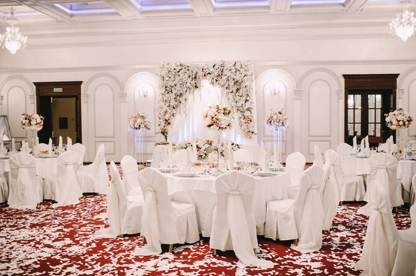 Restoran, ziyafet, sofra kurma. Masa beyaz bir masa örtüsü, bulaşıklar, beyaz temiz tabaklar, çatal bıçak takımı, peçeteler, şarap bardakları, mumlarla kaplı. Yakın plan..