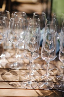 Bir sürü boş şampanya ya da şarap bardağı güneşte parlıyor. Resepsiyon ya da tatil için hazırlık, alkollü içecekler için konteynır. Restoran, yemek servisi, servis.
