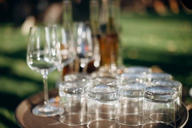 Bir sürü boş şampanya ya da şarap bardağı güneşte parlıyor. Resepsiyon ya da tatil için hazırlık, alkollü içecekler için konteynır. Restoran, yemek servisi, servis.