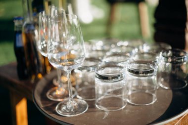 Bir sürü boş şampanya ya da şarap bardağı güneşte parlıyor. Resepsiyon ya da tatil için hazırlık, alkollü içecekler için konteynır. Restoran, yemek servisi, servis.