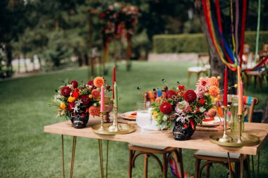 Çok renkli vazolarda, kafatası şeklinde vazolar, dekorda Meksika tarzı çiçekler. Düğün ziyafeti alanındaki şenlik masasında çiçekler ve yeşillik kompozisyonları, mumlar yerleştirilir..