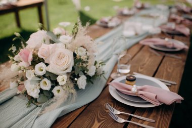 Bir sürü küçük pembe ve beyaz çiçek aranjmanı gül, östoma ve cam vazolarda çeşitli çiçekler. Düğün ziyafeti alanındaki şenlik masasında çiçekler ve yeşillik kompozisyonları, mumlar yerleştirilir..