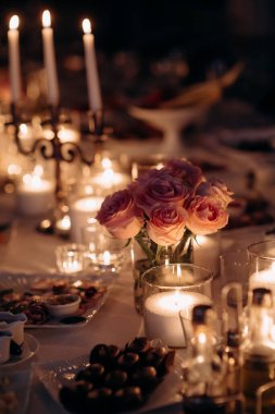 Düğün ziyafetinin olduğu bölgedeki şenlik masasında mumlar çiçek ve yeşillik karışımının şamdanlarına konur..